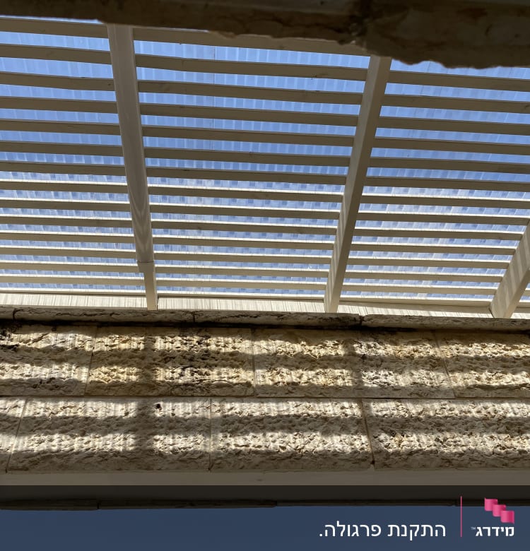 פרגולה מעץ עם קורות לבנות בשמש